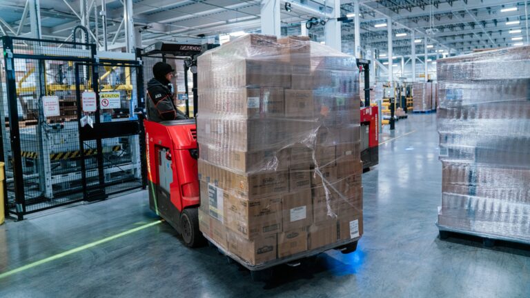 worker driving forklift with cases on it