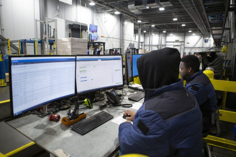 two workers on computers in a facility